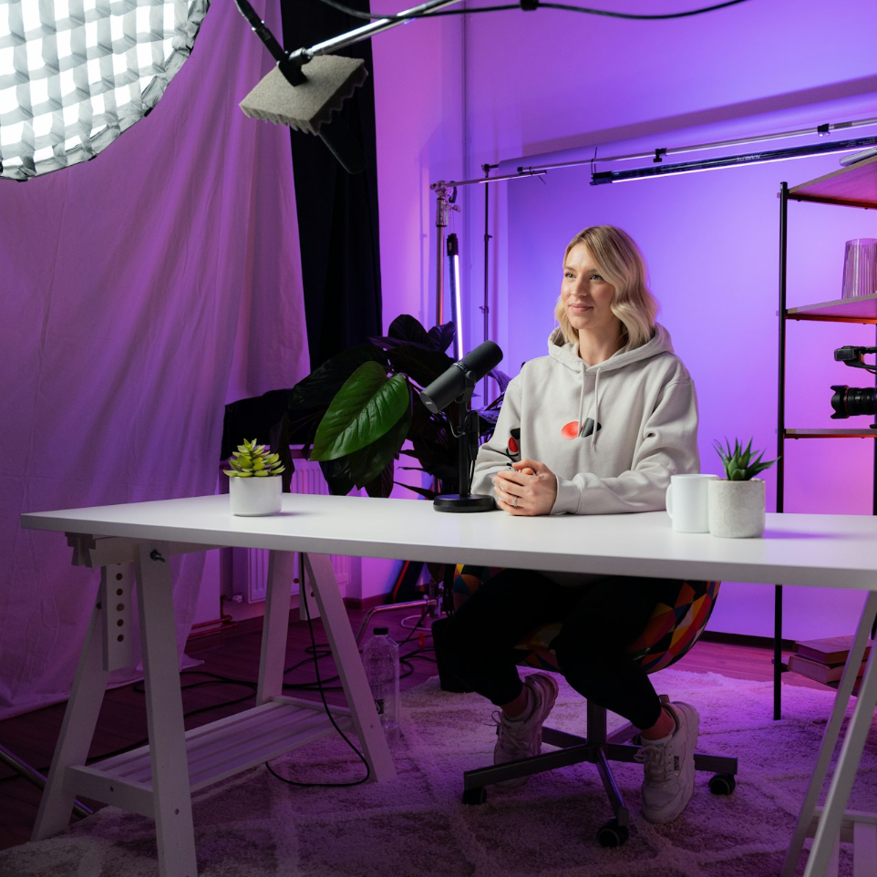 a woman sitting at a table in front of a camera